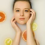 Photographie du visage d'une jeune femme entouré de tranche d'orange et de citron frais